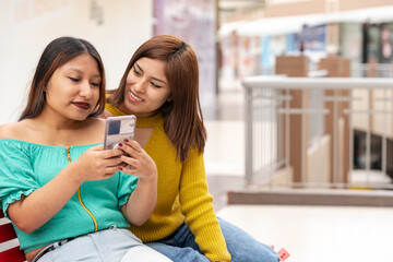 Photo with copy space of friends using a mobile in a shopping mall