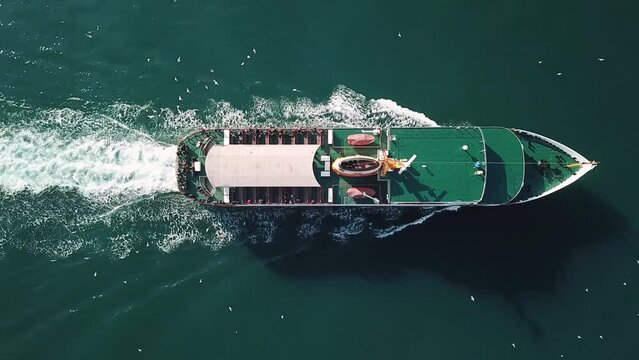 Beautiful trail behind of vintage passenger ship underway offshore. A ferryboat cruising on the sea surface. Engine roars at full speed leaving wake water on Bosphorus Sea. Nice deep green shade of wa