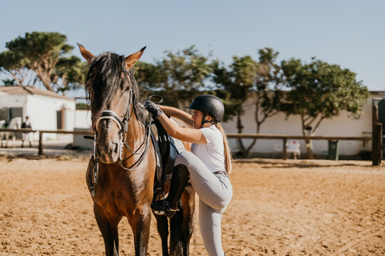 Young Woman In Equestrian Clothing Getting On A Horse