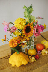 Stylish autumn composition on rustic table. Colorful autumn flowers, pumpkins, pattypan squashes on wooden table in atmospheric room. Harvest in countryside. Happy Thanksgiving! Hello Fall