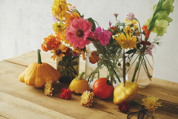 Autumn moody still life, atmospheric image. Colorful autumn flowers, pumpkins, pattypan squashes composition on rustic wooden table. Harvest in countryside. Happy Thanksgiving! Hello Fall