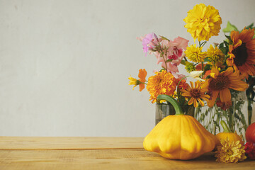 Happy Thanksgiving! Autumn moody still life. Colorful autumn flowers, pumpkins, pattypan squashes composition on wooden table against rustic background. Seasons greeting card, space for text