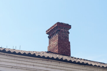 Old red brick chimney pipe against the sky.