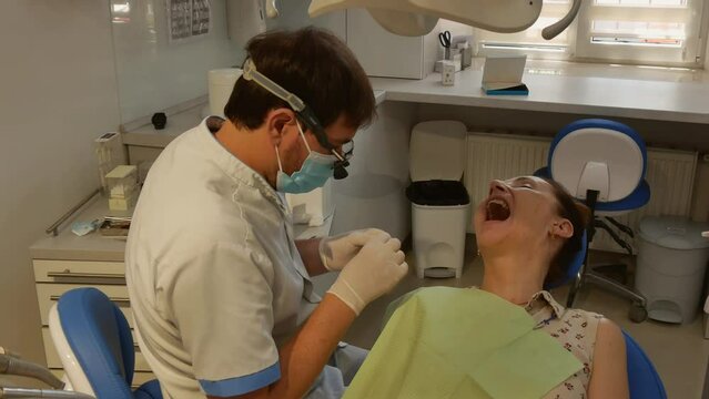 Dental clinic. The doctor prosthetics the teeth of an adult woman.