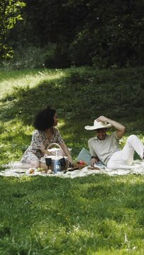 A couple having a romantic picnic in the park with a dog taking a photograph