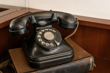 Viejo teléfono negro a disco sobre libro antiguo. Comunicaciones en el siglo XX. 