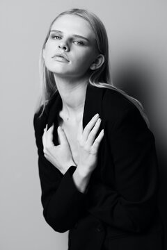 A stylish professional model crosses her arms on her chest and holds a jacket while posing in the studio. Fashionable stylish photo. Concept for clothing brands