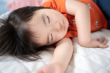 Obraz na płótnie Canvas 布団でお昼寝している2歳の女の子