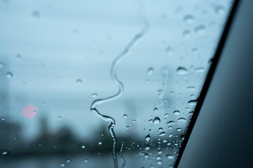 梅雨の日に車の窓ガラスについた雨粒