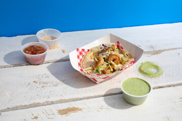 Shrimp tacos and salsas on white wooden table