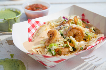 Detail of a shrimp taco on paper plate, white background, mexican food