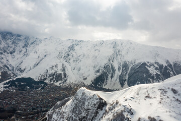 Picturesque rocky landscape of Greater Caucasus mountains on territory of Georgia with view of snow covered peaks in white clouds on sunny spring day