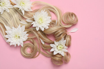 Fototapeta na wymiar Lock of healthy blond hair with flowers on pink background, flat lay. Space for text