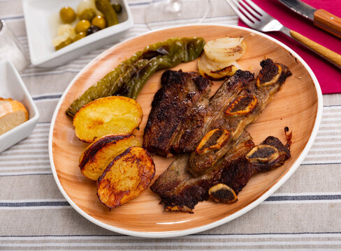 Popular Spanish dish of grilled beef steak Churrasco, potatoes and baked peppers