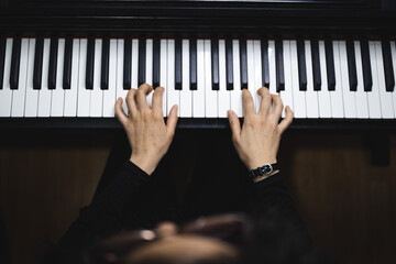 Top view of woman's hands playing piano by reading sheet music. Dark mood.