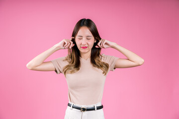 Asian woman finger covering your ear to mute loud noise her unhappy sound expression on the pink...