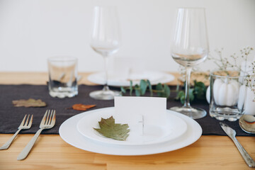 Thanksgiving table setting, tableware and decorations. Blank white postcard on table mockup.