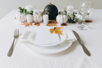 Thanksgiving table setting, tableware and decorations. Blank white postcard on table mockup.