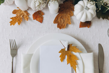 Thanksgiving table setting, tableware and decorations. Blank white postcard on table mockup, top view