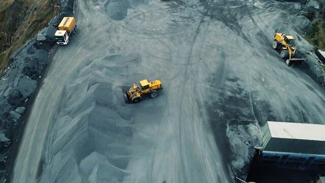 Aerial view of wheel loader working on construction site. Wheel bulldozer loading soil in scoop.