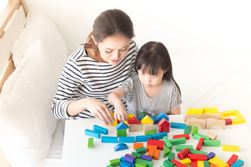 asian baby and her mother play puzzle wood toy, leaning and development