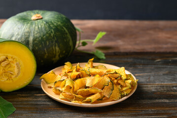 Pumpkin chips on plate with wooden background, Healthy vegan snack