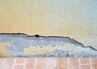 Cracked concrete wall and peeling paint. Wall corrosion concept, earthquake, non-standard construction.