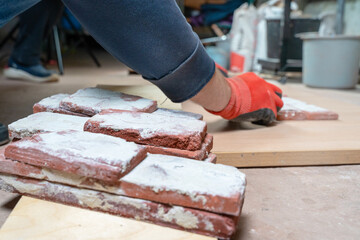Process of making tiles for an old brick. Close-up of gloved hands on a carpenter table with bricks covered with plaster. Various brick texture, handmade. Making casts from old bricks. Loft Art brick 