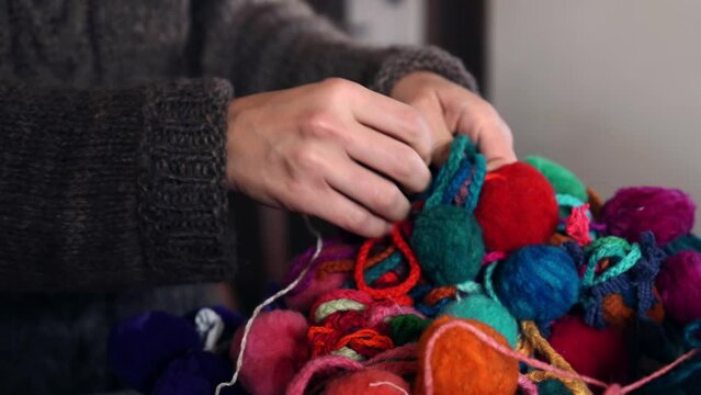 woman's hands unravel balls of wool