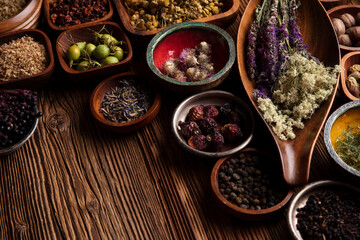 Natural medicine background. Assorted dry herbs in bowls, mortar and plants on rustic wooden table.