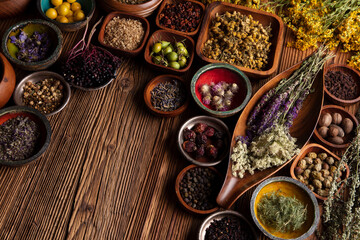 Natural medicine background. Assorted dry herbs in bowls, mortar and plants on rustic wooden table.