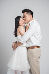 Happy young Asian couple in love embracing and kissing on white background