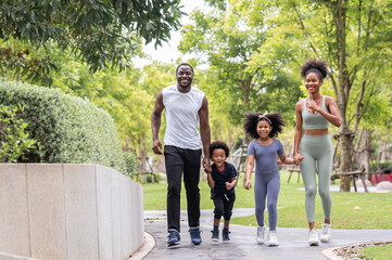 Obraz premium Happy African American family running together outdoor in the park