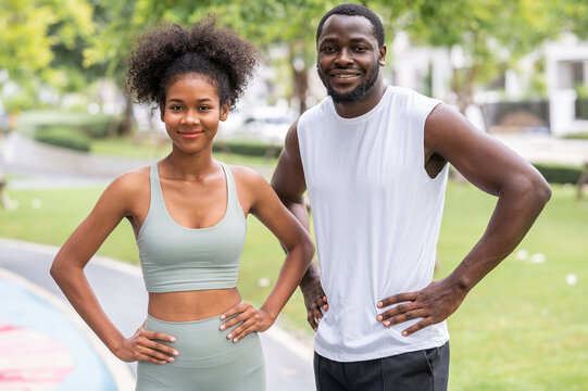 Happy smiling young sporty African American couple standing outdoor in the park