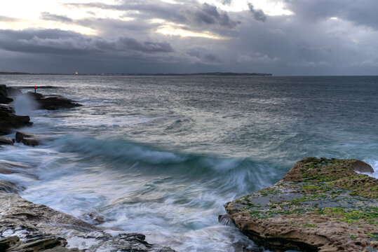 Lone person fishing on rock at moody sunrise