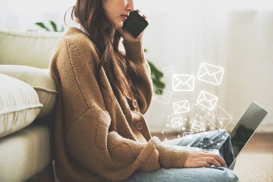 Email marketing and newsletter concept. Woman sitting on the floor and using computer laptop and sending online message with email icon