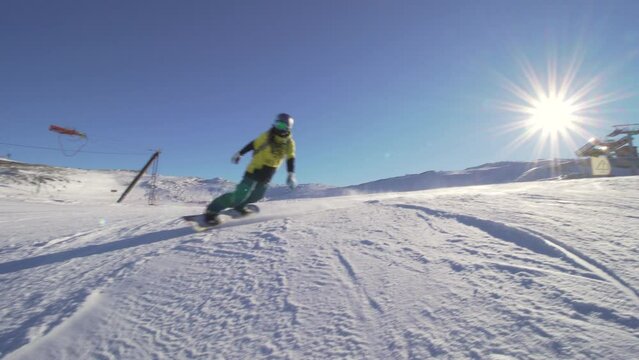 girl snowboarding on slopes in european ski center. female snowboarder passing by. clear blue sky.
