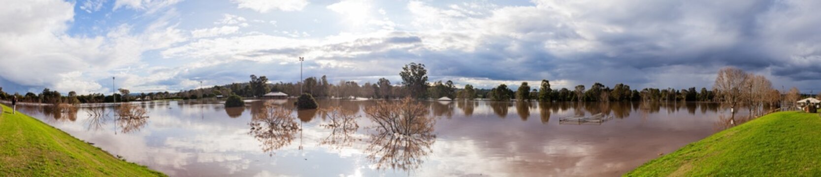Park sports playing fields covered with floodwater seen from levee bank