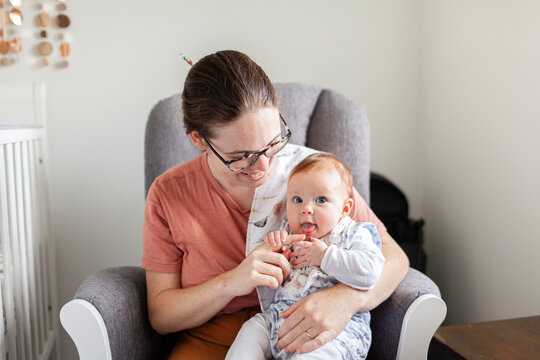 Baby trying to lick mums finger while cuddling together in nursery - oral exploration