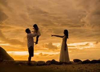 a man is holding his daughter, seen by her mother under golden hour which was the sunrise at one of...