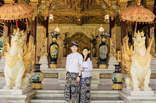 Couple in love in front of a temple. Both are wearing traditional clothes from Bali that were udeng , kamen, and kebaya. 