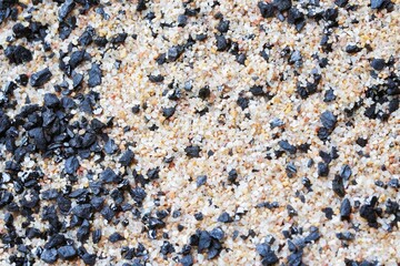 A macro photo of sand grains and piles of black coal.