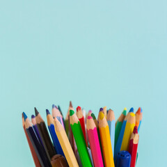 Colorful pencils in tray on blue background