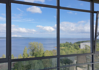 Landscape visible through panoramic window to lake and blue sky with clouds. Aerial view.