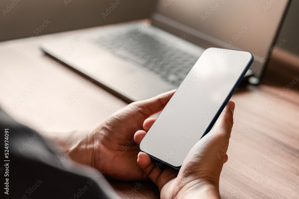 Poster Mockup image of a man holding and using smartphone with blank desktop screen while working and drinking coffee in cafe.