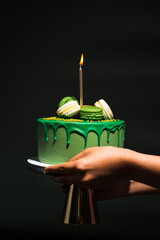 hand holding birthday cake with candles on a black background	
