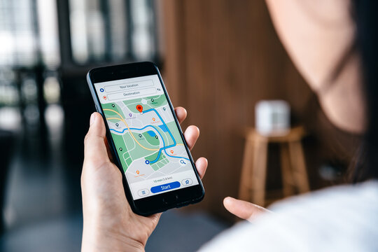 Hand of young woman searching location in map online on smartphone.