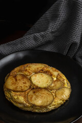 potato and egg omelette with black background