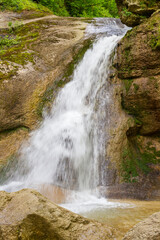 A mountain river in a natural channel with rapids and waterfalls in the bosom of nature.