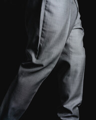 Gray pants on a black background. Fine fabric texture. Elegant suit pants. High quality photo